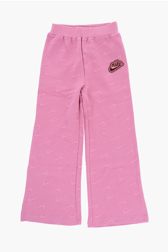 Shop Nike Solid Color Flared Pants With All-over Logo